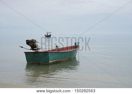 Traditional wooden fishing boat floating on the peace surface wave of the sea,in the afternoon against the blue water,selective focus