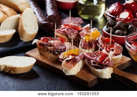 Spanish Tapas With Slices Jamon Serrano And Grilled Pepper. Also Olives, Salami, Pickled Onions, And