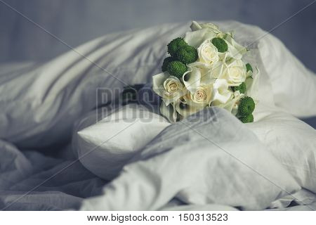 Beautiful wedding bouquet lying on cushions on the bed before the ceremony