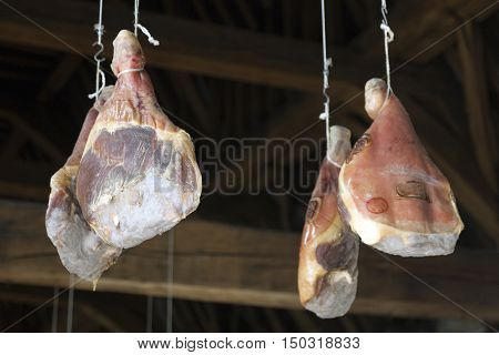 hams hang from very old wooden beams in Ghent Meat Hall