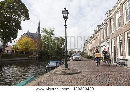 Maarssen, Netherlands, 30 september 2016: couple on bicycle passes houses along river Vecht in the dutch village of Maarssen in the netherlands