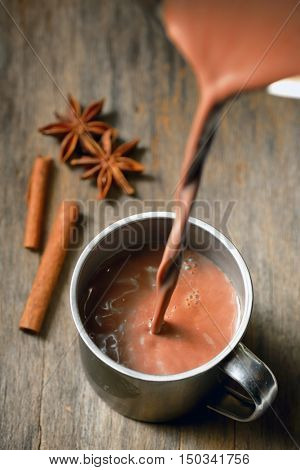 Hot chocolate with cinnamon stick on wooden table