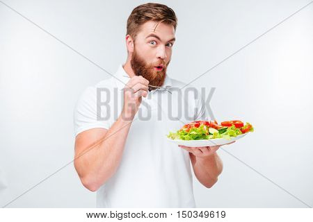 Happy excited bearded man holding plate with fresh sala a,