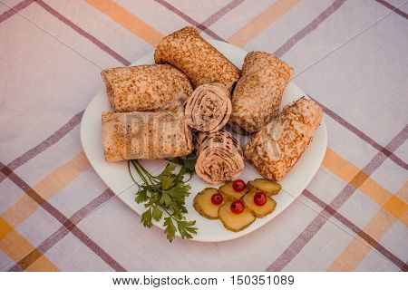 Tasty pancakes with meat on white plate closeup. Crepes stuffed with finely cut meat.