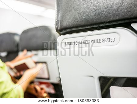 Close up fasten seat belt at backrest on airplane.