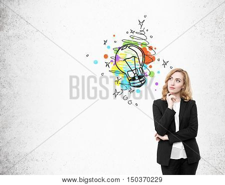 Portrait of red haired businesswoman standing near concrete wall with colorful light bubl sketch. Concept of bright idea. Mock up