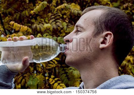 close up of a man drinking water from a bottle outside