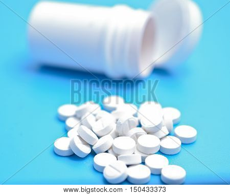 white pills on a blue background with botlle