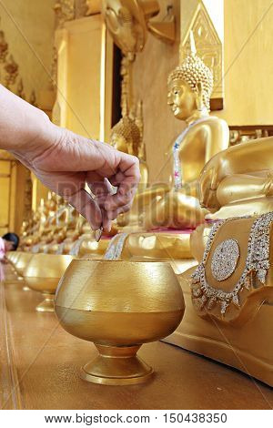 Give coin in alms bowl, a man put a Baht coin in a monk bowl for making merit or donation, buddhism Thai people donating money for temple, row of bowl