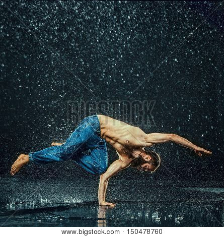 The male break dancer in water on dark background.