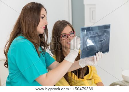 Female dentist showing her patient x-ray radiography, in the Dental Clinc