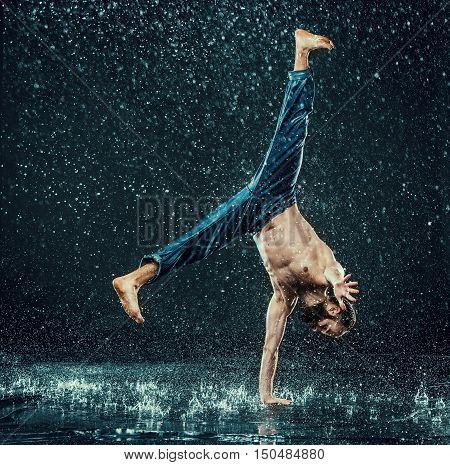 The male break dancer in water on dark background.