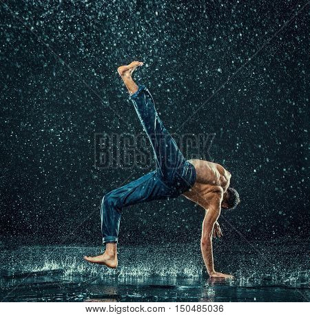 The male break dancer in water on dark background.