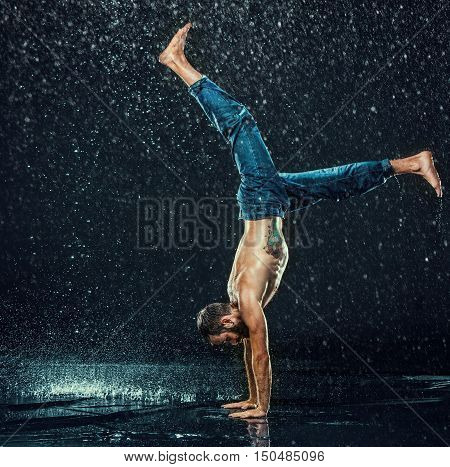 The male break dancer in water on dark background.