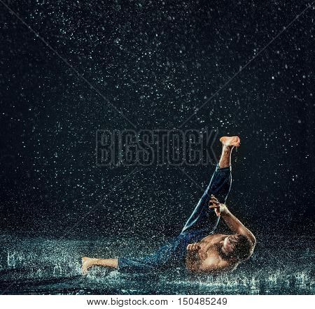 The male break dancer in water on dark background.