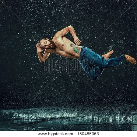 The male break dancer in water on dark background.