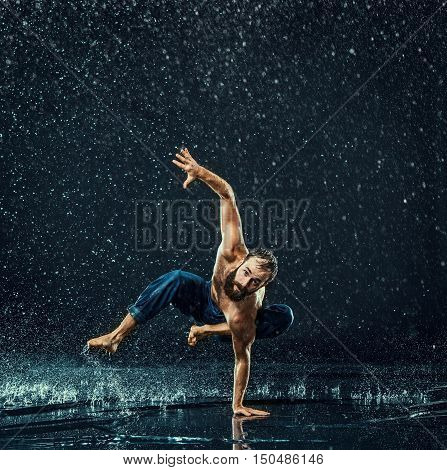 The male break dancer in water on dark background.