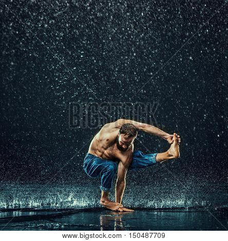 The male break dancer in water on dark background.