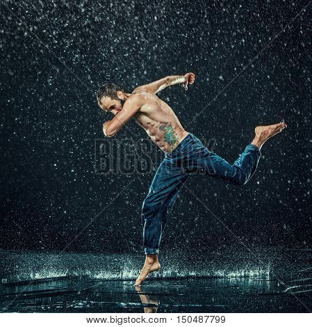 The male break dancer in water on dark background.