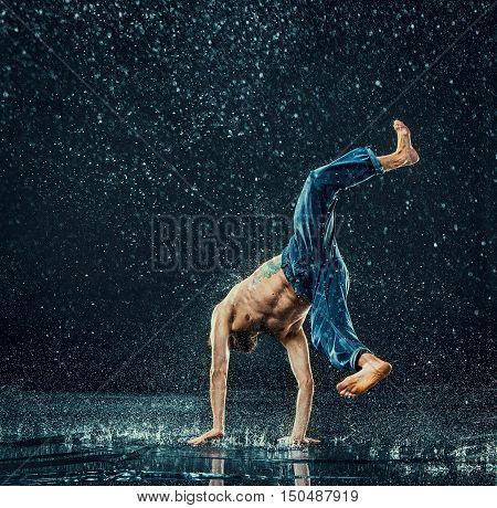 The male break dancer in water on dark background.