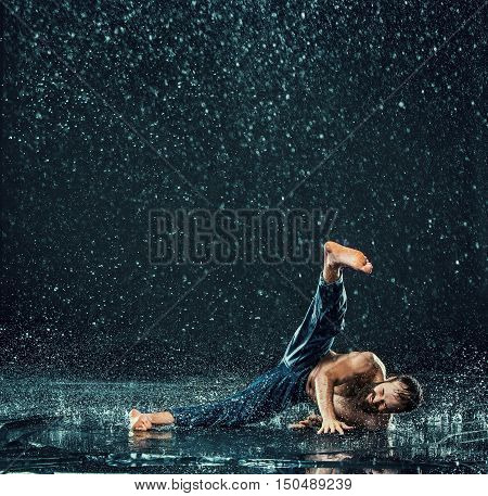 The male break dancer in water on dark background.