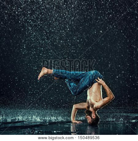 The male break dancer in water on dark background.
