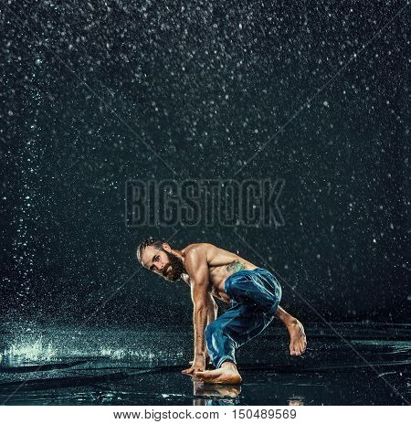 The male break dancer in water on dark background.