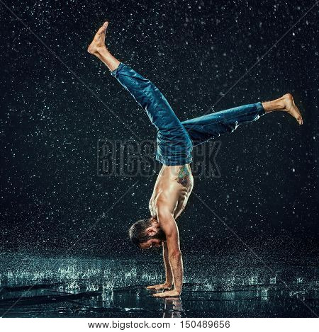 The male break dancer in water on dark background.