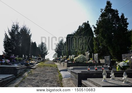 TOPOLCANY SLOVAKIA - 30.10.2015: Graves tombstones and crucifixes on traditional cemetery. Votive candles lantern and flowers on tomb stones in graveyard. All Saints' Day. All Souls' Day