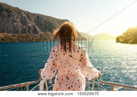 Woman standing ahead on a bow of the boat with beautiful sea scenery