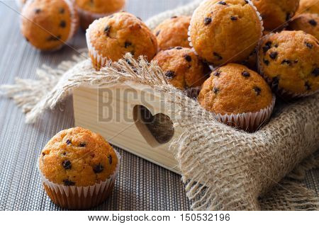 Little chocolate muffins in paper cupcake holder on the wooden tray with sacking napkin