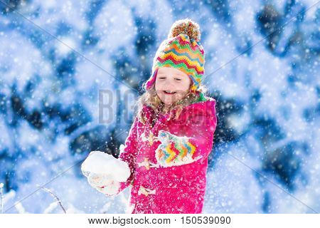 Child running in snowy forest. Toddler kid playing outdoors. Kids play in snow. Christmas vacation in sunny winter park for family with young children. Little girl in colorful jacket and knitted hat.