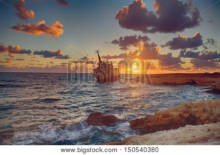 Seascape: old  boat  shipwrecked near the rocky shore at the sunset. Paphos. Cyprus. HDR photo