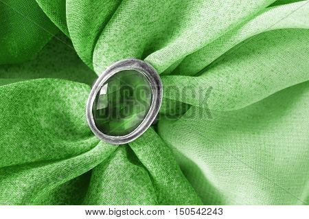 Vintage emerald brooch on green cloth as a background
