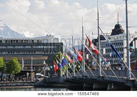 LUCERNE SWITZERLAND - MAY 04 2016: Flags of Switzerland and cantonal waving on the masts fixed to the Seebruecke Bridge that connects the historical and contemporary parts of the city