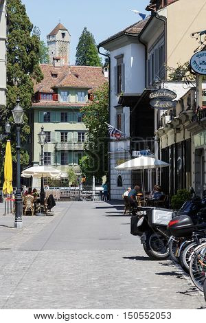 LUCERNE SWITZERLAND - MAY 08 2016: Residential building and the tower of stone that is part of old city walls named Musegg can be seen at the end of the street