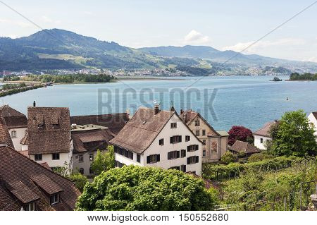 RAPPERSWIL SWITZERLAND - MAY 10 2016: General view towards houses that are covered with tiles and the Lake Zurich waters as seen in the distance