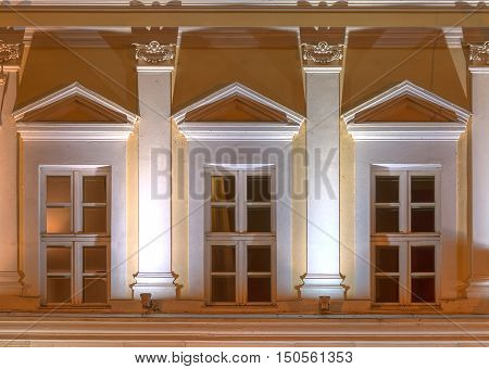 Three windows in a row on night illuminated facade of urban office building front view St. Petersburg Russia