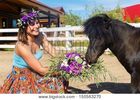 Beautiful girl feeding the straw pony on the farm.