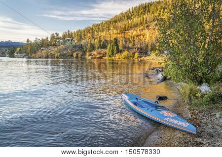 GRAND LAKE,  CO, USA - SEPTEMBER 26: All Star racing stand up paddleboard by Starboard in brushed carbon layout with Werner paddle on a shore of Grand Lake.