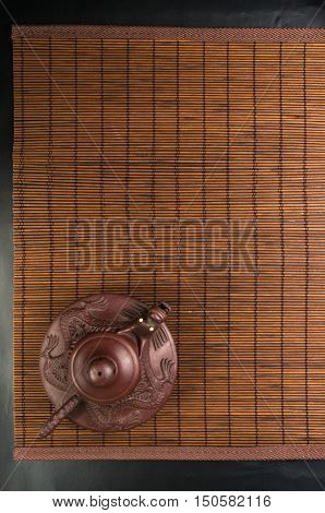 brown Chinese teapot of Yixing clay with traditional ornament on bamboo Mat