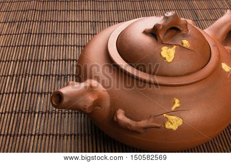 brown Chinese teapot of Yixing clay with traditional ornament on bamboo Mat
