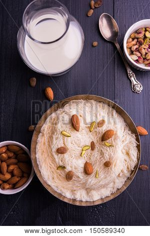 Indian sweet sutarfeni or sutar feni or firni or seviyan or laccha, shredded, flaky-rice-flour roasted in ghee, blended with melted sugar to form a cotton candy, topped with pistachio and almonds