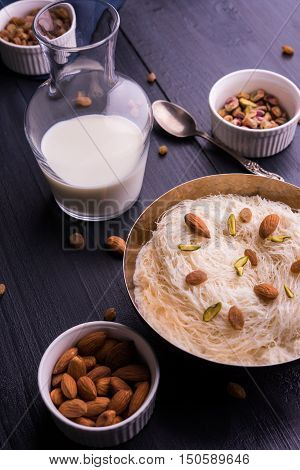 Indian sweet sutarfeni or sutar feni or firni or seviyan or laccha, shredded, flaky-rice-flour roasted in ghee, blended with melted sugar to form a cotton candy, topped with pistachio and almonds