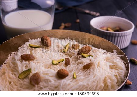 Indian sweet sutarfeni or sutar feni or firni or seviyan or laccha, shredded, flaky-rice-flour roasted in ghee, blended with melted sugar to form a cotton candy, topped with pistachio and almonds