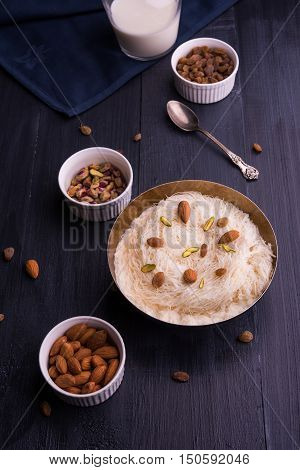 Indian sweet sutarfeni or sutar feni or firni or seviyan or laccha, shredded, flaky-rice-flour roasted in ghee, blended with melted sugar to form a cotton candy, topped with pistachio and almonds
