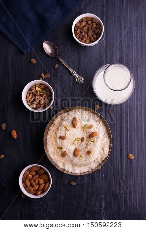 Indian sweet sutarfeni or sutar feni or firni or seviyan or laccha, shredded, flaky-rice-flour roasted in ghee, blended with melted sugar to form a cotton candy, topped with pistachio and almonds