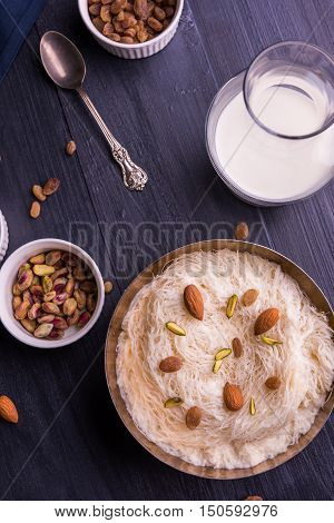 Indian sweet sutarfeni or sutar feni or firni or seviyan or laccha, shredded, flaky-rice-flour roasted in ghee, blended with melted sugar to form a cotton candy, topped with pistachio and almonds