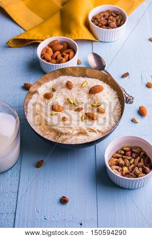 Indian sweet sutarfeni or sutar feni or firni or seviyan or laccha, shredded, flaky-rice-flour roasted in ghee, blended with melted sugar to form a cotton candy, topped with pistachio and almonds