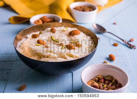 Indian sweet sutarfeni or sutar feni or firni or seviyan or laccha, shredded, flaky-rice-flour roasted in ghee, blended with melted sugar to form a cotton candy, topped with pistachio and almonds